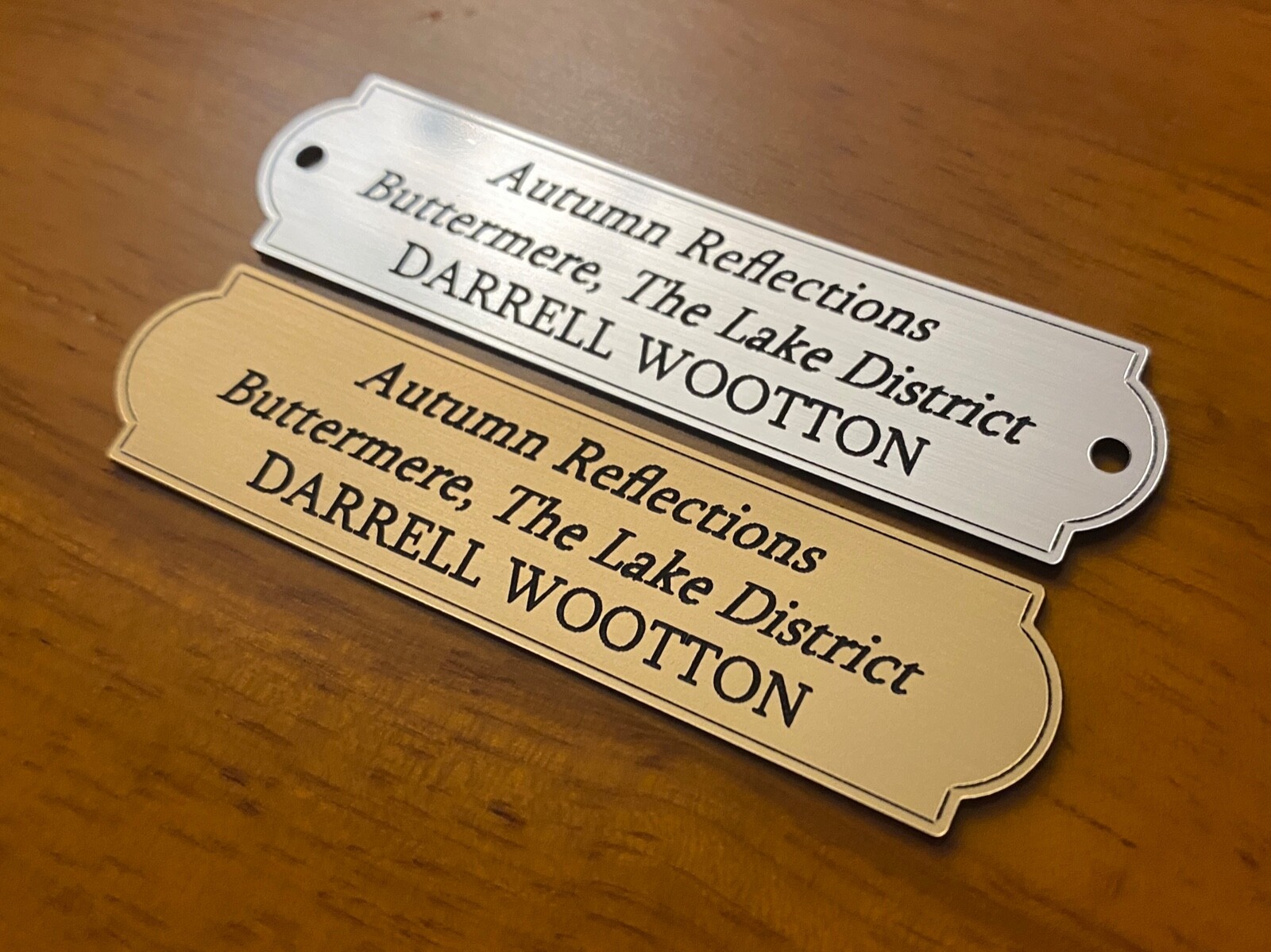 Silver and gold rounded-border plaques with three lines of text and fixing holes